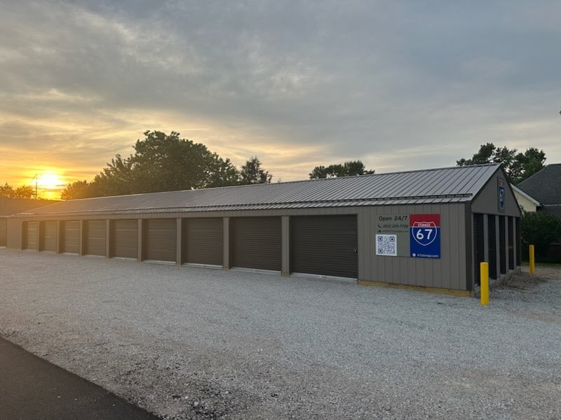 Overview of 67 Storage Facility in Worthington, Indiana, with multiple storage units and a sunset in the background.